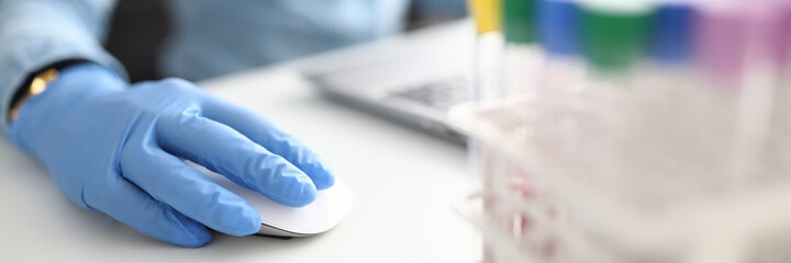 Female hand in rubber glove holds computer mouse in chemical laboratory closeup. Laboratory diagnostics data systematization concept.
