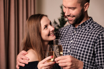 A young woman and a man drink champagne together in glasses. Christmas and new year celebrations.