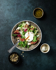 prosciutto, figs, arugula, goat cheese salad with pecan nuts and balsamic sauce, black background, top view, close up, copy space. Healthy food. poached egg. jamon