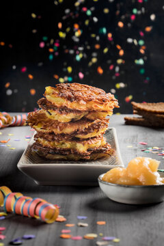 A stack of potato fritters with apple sauce and carnival decorations