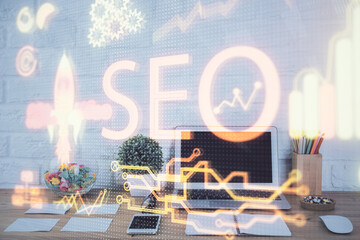 Double exposure of table with computer and seo drawing hologram. Search optimization concept.