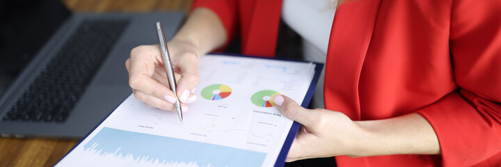 Woman in red jacket signs document on clipboard a table with colleague in office closeup. Marketing...