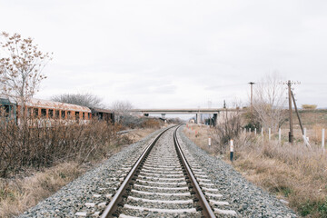 Fototapeta na wymiar train tracks leading to the horizon in abandoned railway ghost station rust bridge in winter cloudy in greece