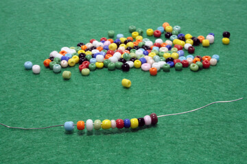 Multi colored beads spread on green background.