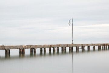 misty foggy smooth waters of a pier in greece with lamppost  simple minimalist
