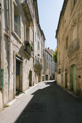 street view of narrow alley road lane in the sun and shadow leading the town city in summer in montpellier france old early building