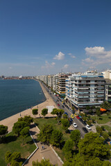 elevated view on thessaloniki during summer showing buildings by the sea, and a walking walk path by the water blue skies some clouds, port further down