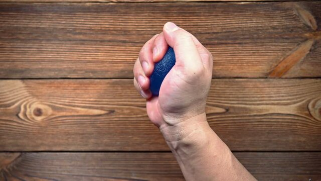 man doing exercises by squeezing a rubber hand trainer