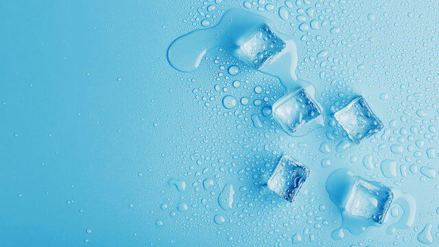 Ice cubes with drops of melt water water on a blue background, top view.