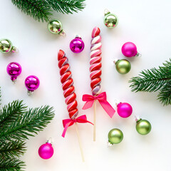 Christmas flat lay of lollipops, balls and fir branches on white background, top view