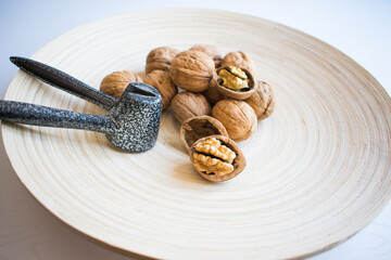 cracked walnuts and whole walnuts in a wooden plate.