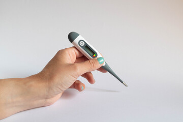 Hand holding a digital thermometer turned off on white background