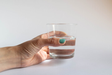 Hand holding a glass half empty or half full on white background