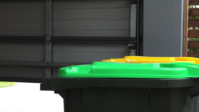 Adult woman collecting rubbish bin from road side on rubbish day