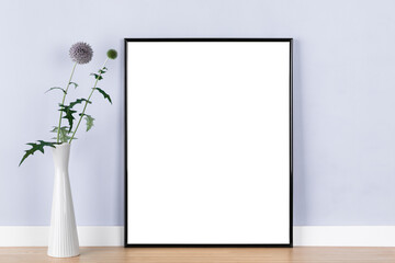 Poster artwork mockup template with black picture frame and globe thistle in vase in front of pastel purple wall, blank image area masked with clipping path