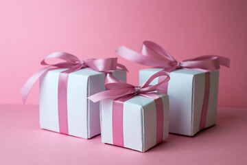Gift or present box with shiny balls, ribbons and snowflakes on pink background. Flat lay composition for christmas, female Christmas. White gift with pink ribbons. A gift box isolated on pink 