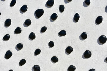 White wall with black stones background. Black and white texture.