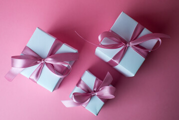 Gift or present box with shiny balls, ribbons and snowflakes on pink background. Flat lay composition for christmas, female Christmas. White gift with pink ribbons. A gift box isolated on pink 