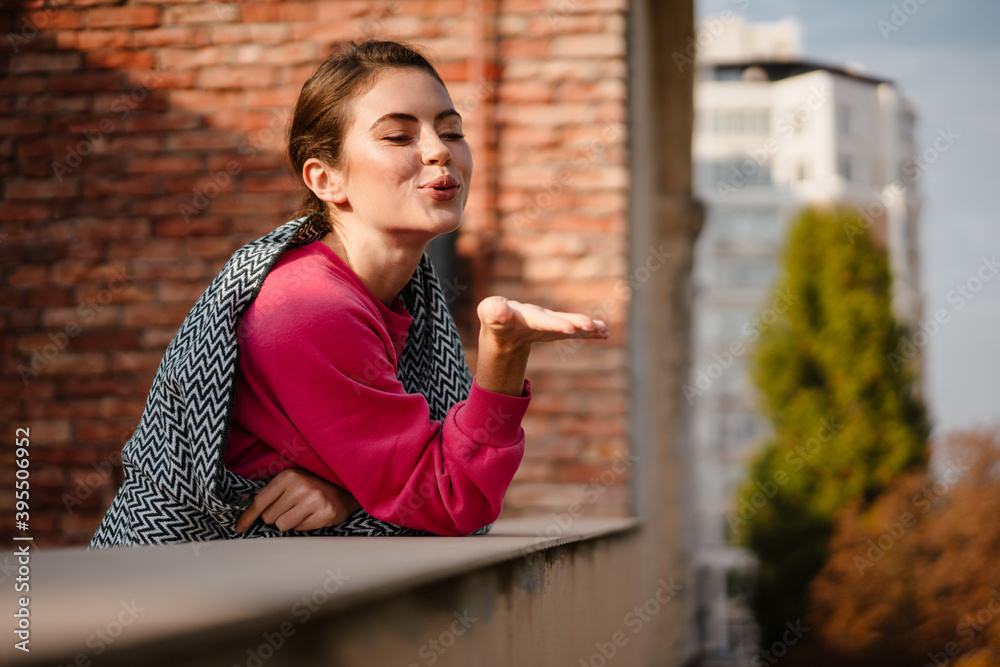 Wall mural charming cheerful girl smiling while standing on balcony outdoors