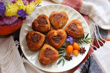 Six heart shaped cupcakes decorated with grated chocolate and small kumquats