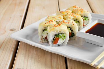 Portion of rolls with salmon, cucumber and cheese in marinated ginger dressing with golden sesame