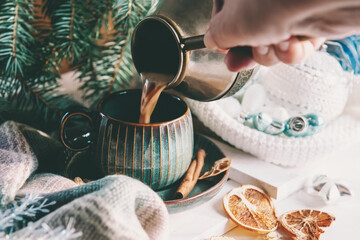 Hand pours Hot coffee or chocolate. Christmas still life on the Christmas table. Hot winter drinks in a cozy home still life