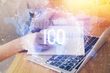Cryptocurrency hologram, bitcoin, ico theme over hands taking notes background. Concept of...