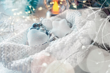 Glass Christmas decorations in the form of a snow heart are ready to dress up the Christmas tree. Christmas decor with toys, garlands and fir branches. Bokeh and glare. Selective soft focus