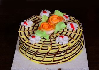 beautiful and tasty birthday cake with dark background and cream flowers on top