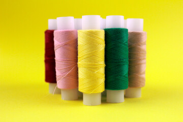 Heap of multicolored sewing thread on yellow background