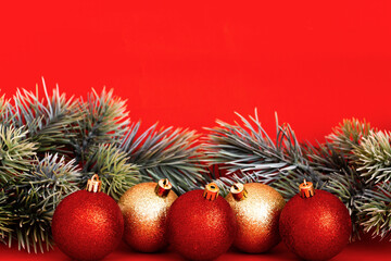 Red glittering Christmas balls and pine branch on a red background. New year and christmas concept. Minimal festive composition. copy space for text.