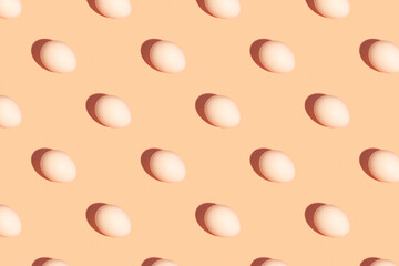 Seamless regular pattern of fresh eggs on a pastel orange background. Hard light. Easter holiday concept.