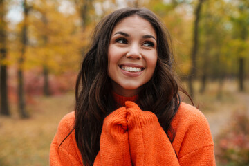 Beautiful brunette happy woman smiling while strolling in autumn forest