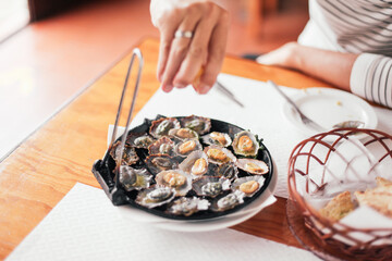 Traditional food from Madeira - fried limpets - 'lapas' on a table, squeezing lemon juice on top