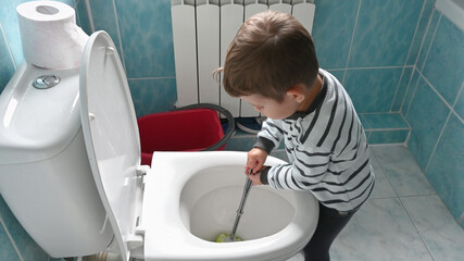 Young toddler boy cleans and disinfects the bathroom and toilet. Fun child's play at home. Little...