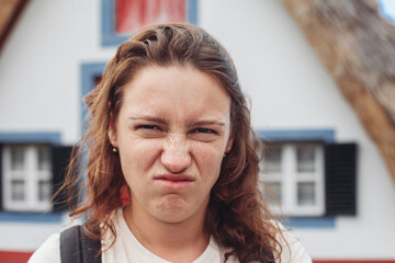 A young woman looks disgusted and unsatisfied, outdoors 