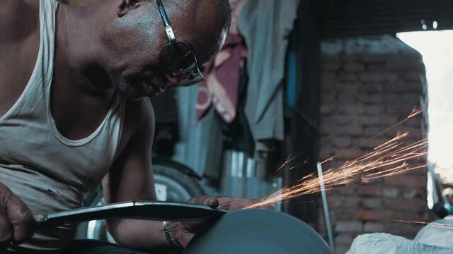 Man sharpening large metal knife on rotating grinder in slow motion