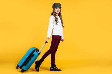 teen girl with suitcase for trip on yellow background, adventure