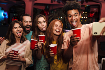 Smiling friends with smartphone taking selfie