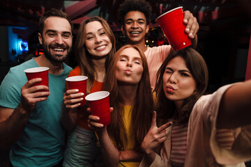 Smiling friends with smartphone taking selfie