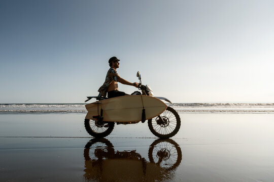 Real balinese surfer with motorcycle and surfboard 