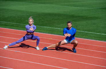 Obraz premium healthy lifestyle. muscle flexibility. sport couple stretching. fitness partners warming up. athletic man and sexy woman training. male and female coach on stadium do squat lunge