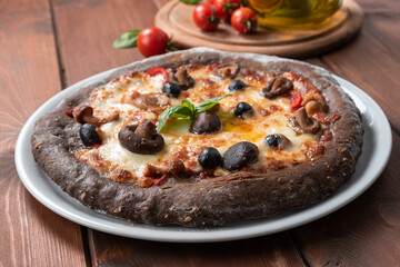 Pizza nera con impasto ai cereali e condita con mozzarella e funghi 