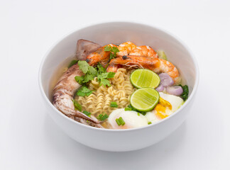 Tom Yum Kung is favorite taste of Thai cuisine with yellow noodle and vegetable ingredient in the white bowl. 