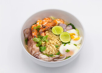 Tom Yum Kung is favorite taste of Thai cuisine with yellow noodle and vegetable ingredient in the white bowl. 