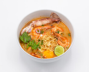 Tom Yum Kung is favorite taste of Thai cuisine with yellow noodle and vegetable ingredient in the white bowl. 