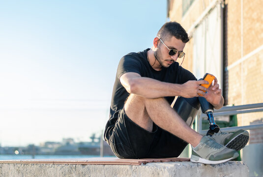 Young handsome man with prosthetic leg standing outdoors. International Disability Day - Powered by Adobe