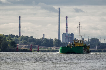SCOW ON THE WATERWAY - A barge on the background of the coast with industrial chimneys

