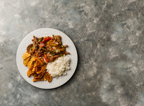 Lomo saltado - Peruvian beef tenderloin with red onions, yellow chili, tomatoes, with potato fries and rice