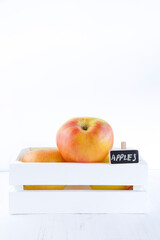 White wooden box full of fresh apples and a little chalkboard isolated on a white background